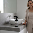 Load image into Gallery viewer, Woman standing next to a bottle of Australian Eucalyptus Bench Spray on a bathroom vanity.

